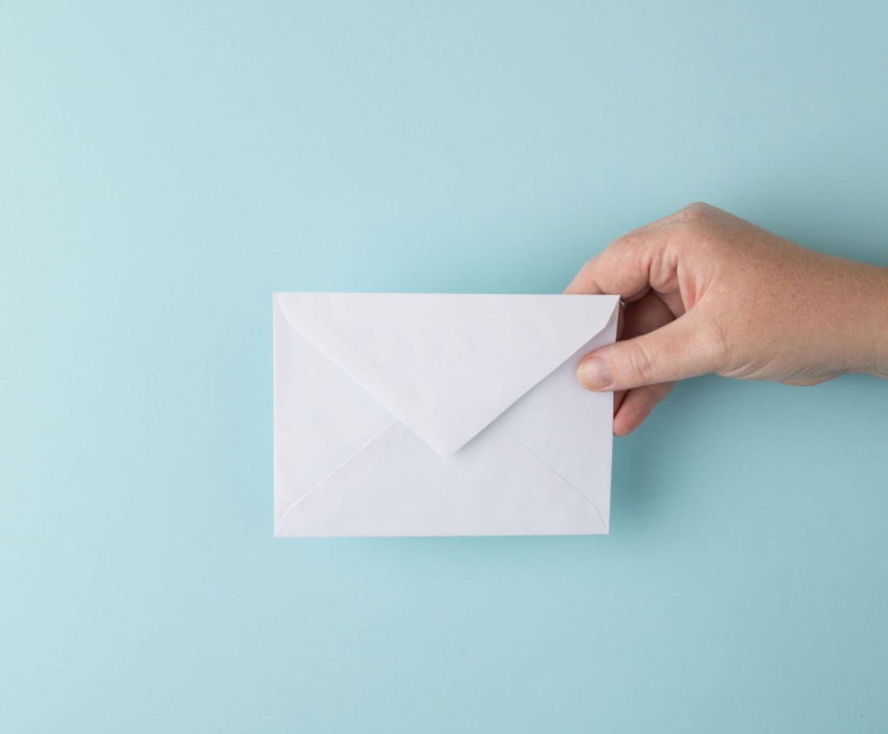 Hand holding white envelope